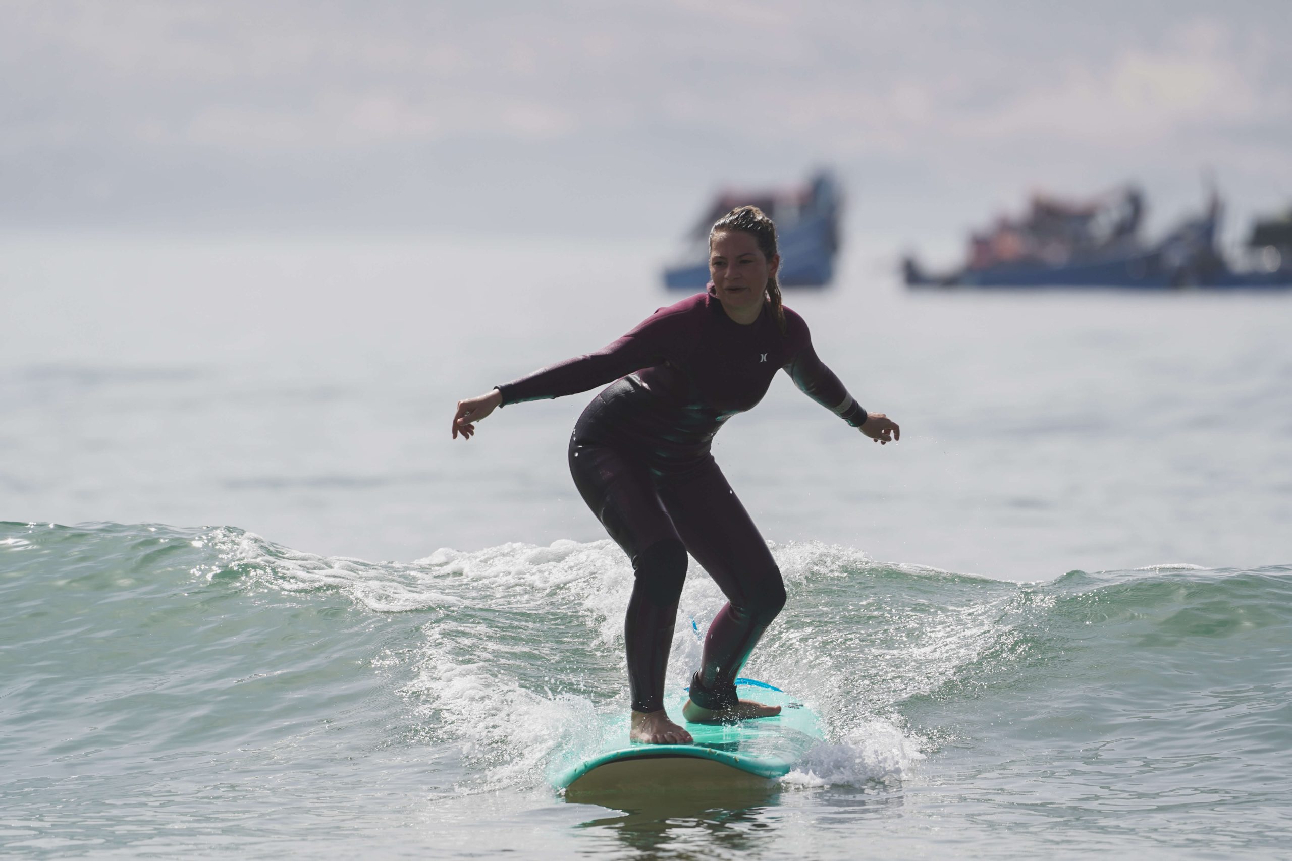 Beginner surfer girl surfing small green wave