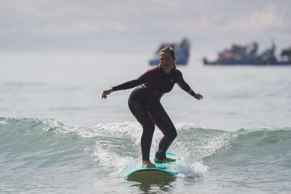 Une surfeuse surfe la vague verte en combinaison Hurley
