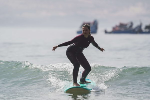 Anfänger Surferin reitet eine Welle in Marokko mit Hurley Wetsuit