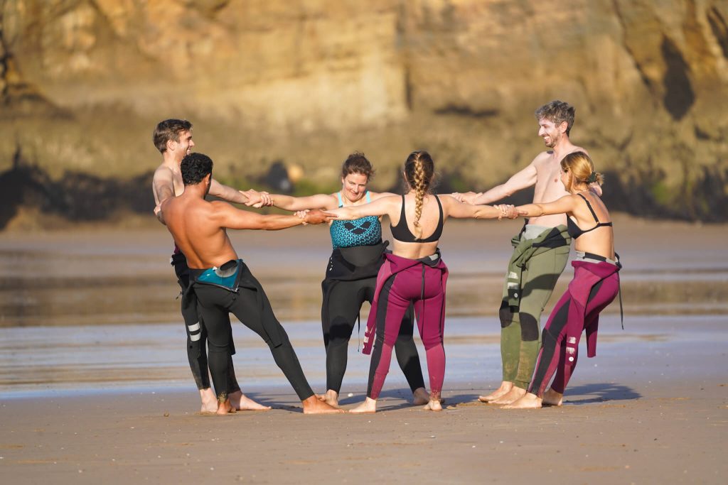 Les surfeurs débutants s'étirent sur la plage avec un moniteur de surf