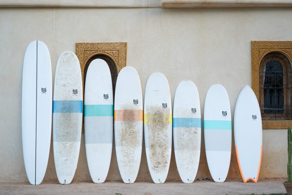 Surfboards in different shapes and sizes lined up in front of a wall