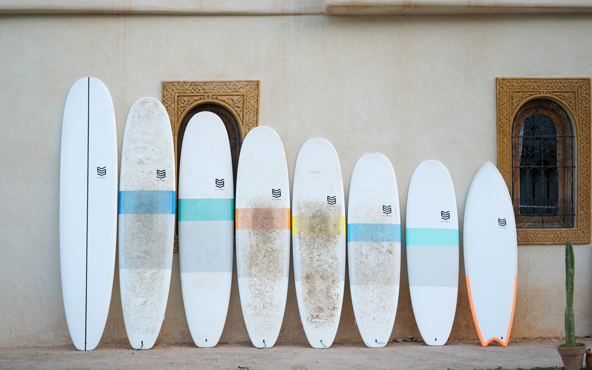 Des planches de surf de différentes tailles et formes appuyées contre un mur de maison au Maroc