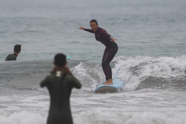 Surfeur débutant surfant sur une petite vague avec un instructeur de surf sur la plage
