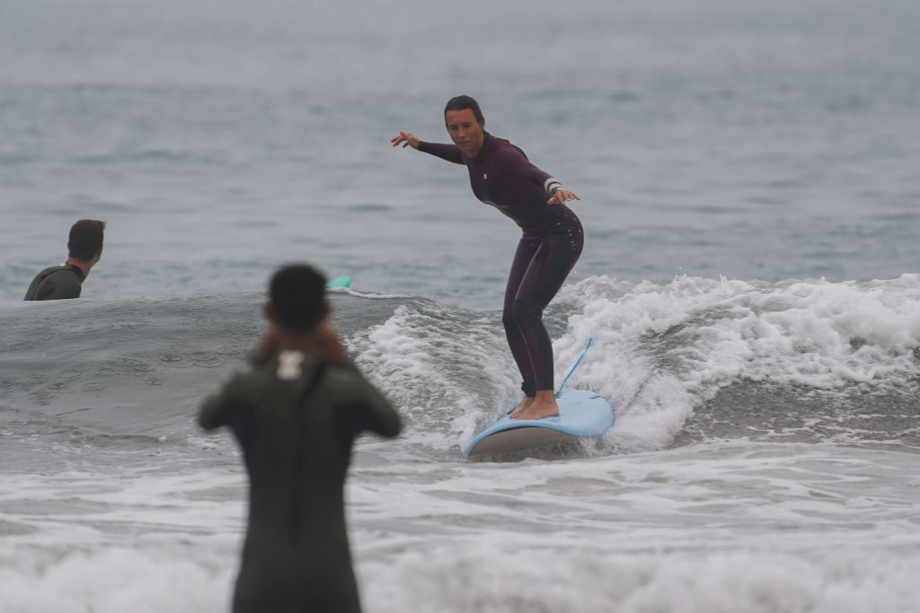 Surferin auf kleiner Welle mit Surflehrer