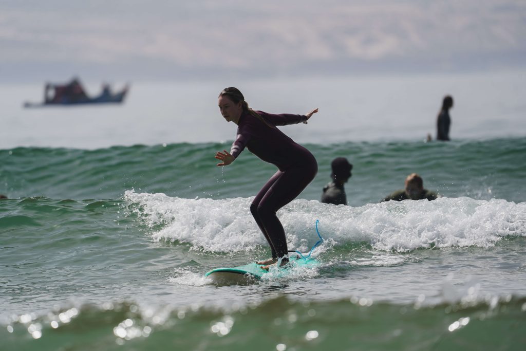 Surferin mit ausgestreckten Armen reitet kleine Welle