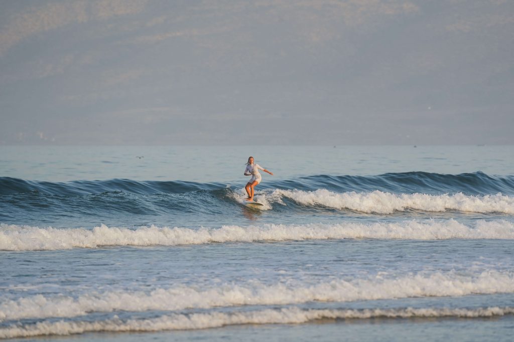Surferin in kurzem Wetsuit surft grüne Welle