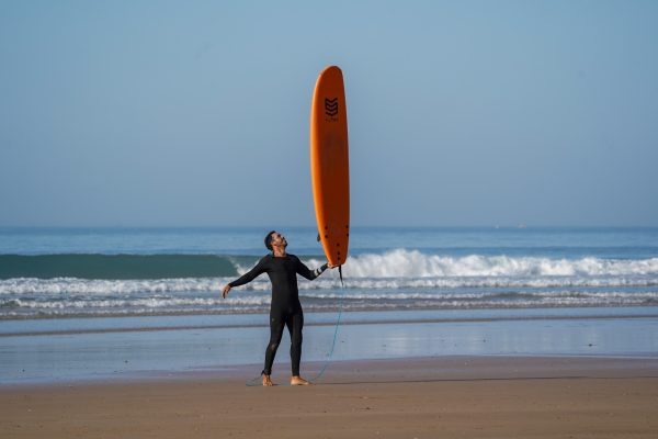 Surfcoach balancing a surfboard on one hand on the beach