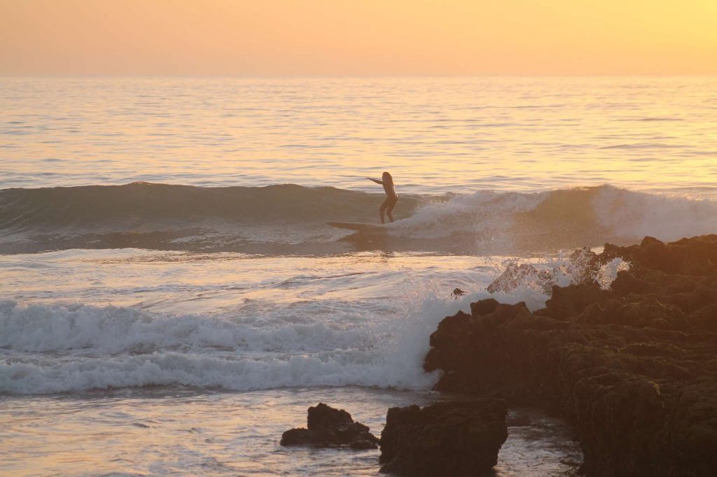 Surfer Riding Devils Rock at Sunset